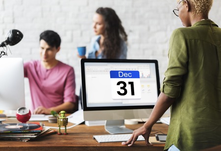 Three marketing professionals gather around a monitor showing an upcoming deadline.